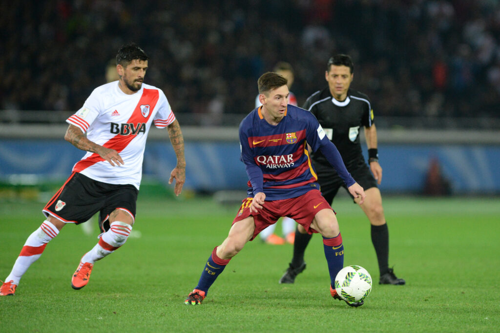 3 soccer players and a referee with a ball